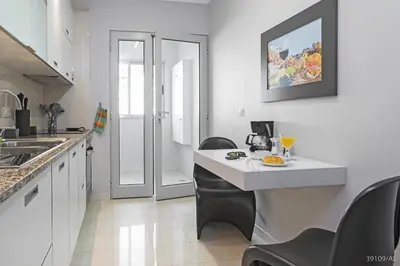 a kitchen with a white counter and black chairs at Santa Catarina l by An Island Apart in Funchal
