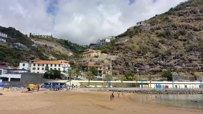 a group of people on a beach with a mountain at Estrela do Mar - Alojamento Local in Calheta