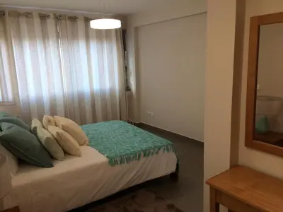 a bedroom with a bed with pillows and a mirror at Apartamentos Sousa in Funchal