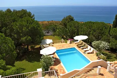 a swimming pool with umbrellas and the ocean at Top Cliff Villa with Ocean View and Private Pool UP to 18 Guests in Burgau