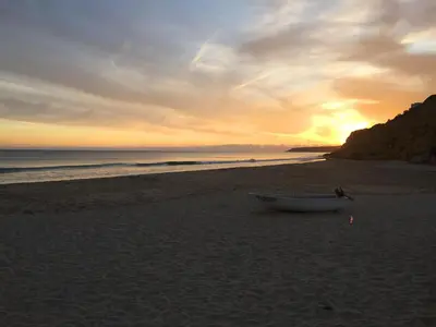 a boat sitting on the beach at sunset at Top Cliff Villa with Ocean View and Private Pool UP to 18 Guests in Burgau