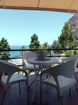 a table and chairs on a balcony with a view of the ocean at Apartamento Vai Vem in Madalena do Mar