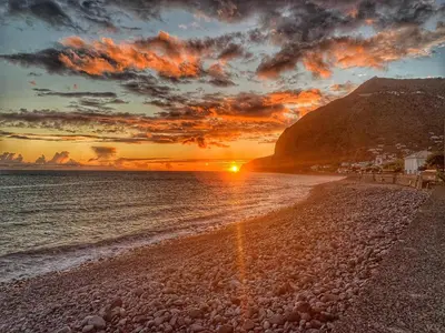 a sunset on a beach with the sun setting at Apartamento Vai Vem in Madalena do Mar