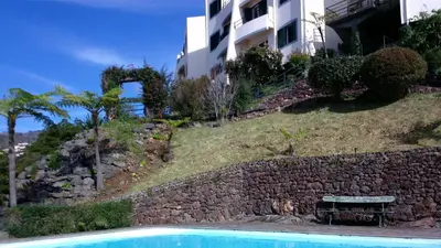 a swimming pool next to a stone wall and a building at Bay View Apartment in Funchal