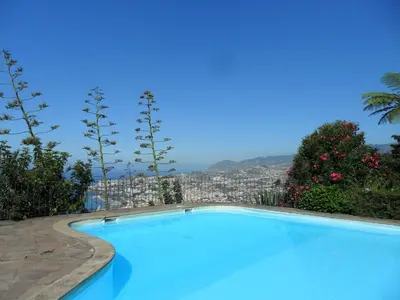 a blue swimming pool with a city in the background at Bay View Apartment in Funchal