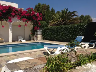 a swimming pool with chairs and flowers in a yard at Great view to sea, villa with pool in Salema
