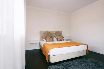 a white bedroom with a bed with an orange blanket at Casa Branca in Funchal