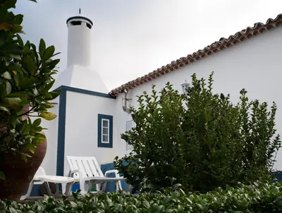 a white building with two white chairs and a lighthouse at Casa do Norte - Santa Maria in Norte