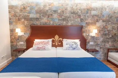 a bedroom with a bed with a wooden headboard and pillows at Quinta da Paz in Caniço