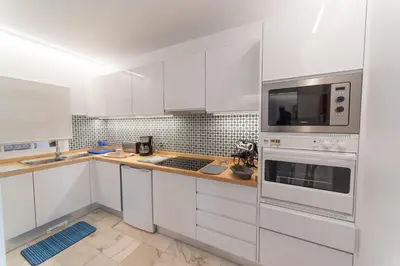 a white kitchen with white cabinets and a microwave at Quinta da Paz in Caniço