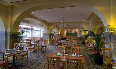 a dining room with tables and chairs and a chandelier at Pestana Madeira Beach Club in Funchal
