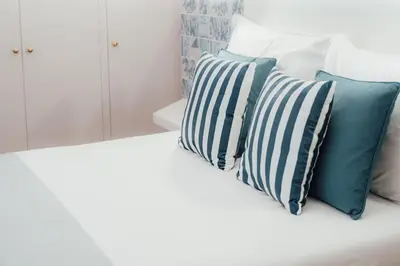 a white bed with blue and white pillows on it at Sé Boutique Hotel in Funchal
