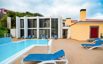 a villa with a swimming pool and blue lounge chairs at Hotel Solar Bom Jesus in Santa Cruz