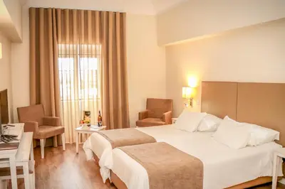 a hotel room with two beds and a window at Hotel Solar Bom Jesus in Santa Cruz