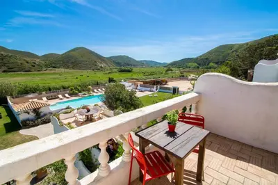 a balcony with a table and chairs and a pool at Casa Fajara in Carrapateira