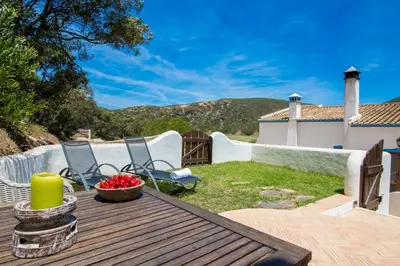 a patio with a table and chairs on a deck at Casa Fajara in Carrapateira