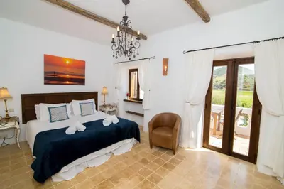 a bedroom with a bed and a chair and a window at Casa Fajara in Carrapateira