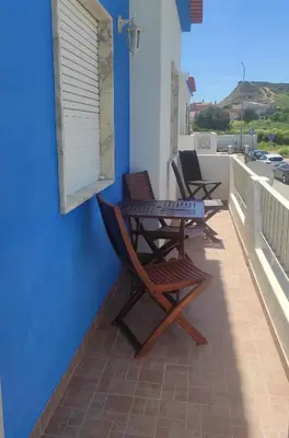 a patio with two chairs and a table on a balcony at Casa Furtado in Burgau