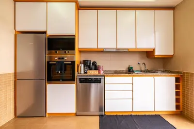a kitchen with white cabinets and a stainless steel refrigerator at Casa Agrela by Rent2U, Lda Swimming Pool & Jacuzzi in Calheta