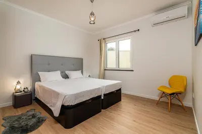 a bedroom with a large bed and a yellow chair at Casa Agrela by Rent2U, Lda Swimming Pool & Jacuzzi in Calheta