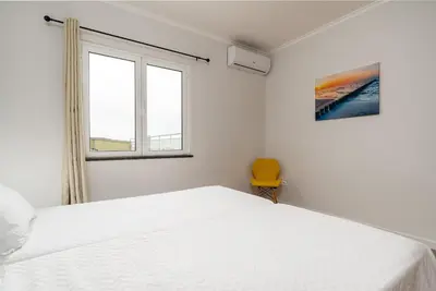 a white bedroom with a white bed and a yellow chair at Casa Agrela by Rent2U, Lda Swimming Pool & Jacuzzi in Calheta