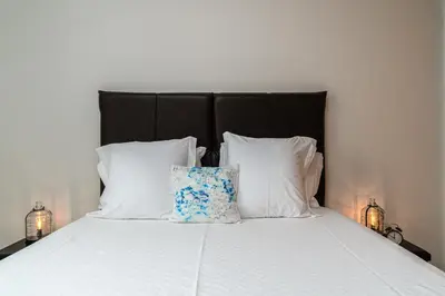 a bed with a black headboard and white pillows at Casa Agrela by Rent2U, Lda Swimming Pool & Jacuzzi in Calheta