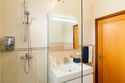 a bathroom with a sink and a shower with a mirror at Casa Agrela by Rent2U, Lda Swimming Pool & Jacuzzi in Calheta