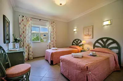 a bedroom with two beds and a table and a window at Luz casas- 44 Fairview village Boavista in Lagos