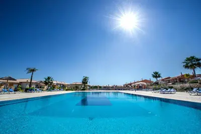 a large blue swimming pool next to a beach at Luz casas- 44 Fairview village Boavista in Lagos