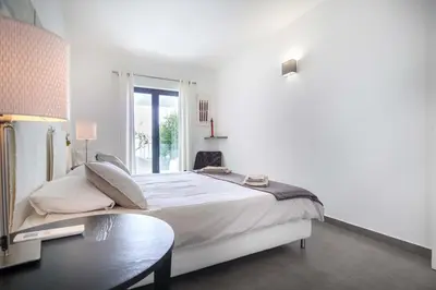 a white bedroom with a large bed and a table at Beco Do Poço in Luz