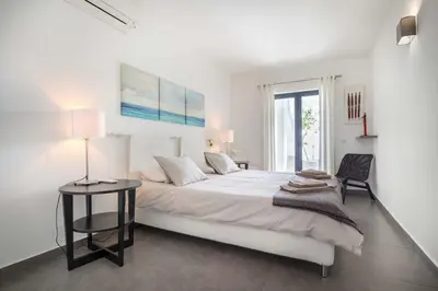 a white bedroom with a large bed and a table at Beco Do Poço in Luz