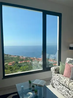 a living room with a couch and two large windows at Casa Vista do Ledo in Arco da Calheta