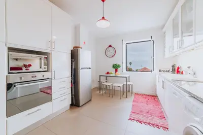 a white kitchen with a refrigerator and a table at Funchal Old Town Apartments 2.8 in Funchal