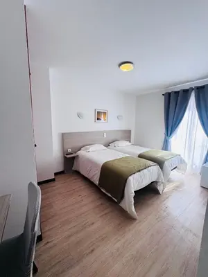 a bedroom with two beds and a large window at Residencial Santo António in Santa Cruz