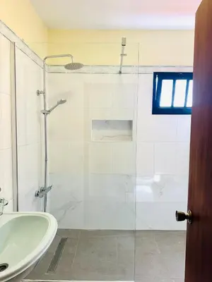 a bathroom with a glass shower and a sink at Residencial Santo António in Santa Cruz