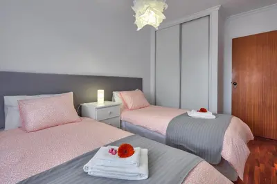 two beds in a room with pink and gray at Golden Place Apartment in Funchal