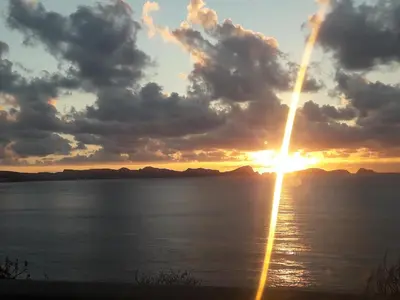 a sunset over the water with mountains in the background at Marques House in Machico