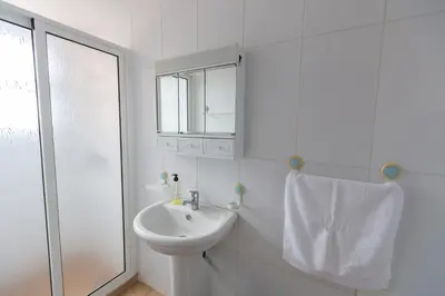 a white bathroom with a sink and a shower at Casa do Avo in Arco da Calheta