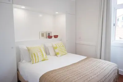 a white bedroom with a bed with yellow and white pillows at Casa Do Mercado by Heart of Funchal in Funchal