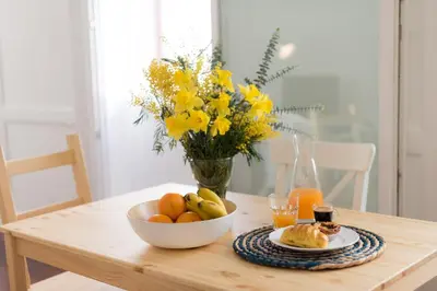 a table with a bowl of fruit and a vase of flowers at Casa Do Mercado by Heart of Funchal in Funchal