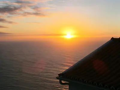 a sunset over the ocean with the sun in the sky at Casa da Ladeira in Fajã da Ovelha