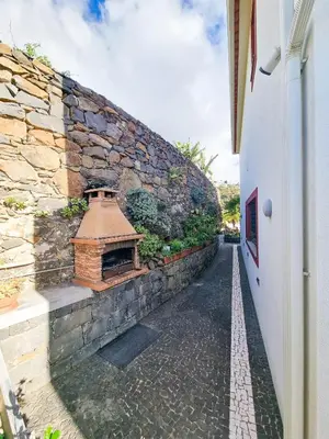 a stone wall next to a building with a bird house at Casa da Ladeira in Fajã da Ovelha