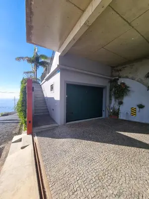 a building with a garage with a large door at Casa da Ladeira in Fajã da Ovelha