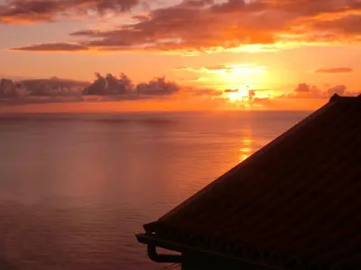 a sunset over the ocean with the sun setting at Casa da Ladeira in Fajã da Ovelha