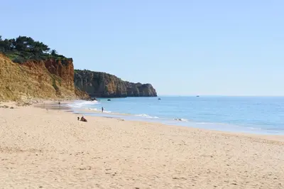 a beach with people sitting on the sand and the ocean at Porto de Mos Golf & Beach B&B AL-40312 in Lagos