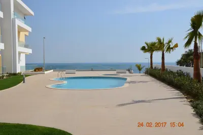 a swimming pool next to a building and the ocean at Porto de Mos Golf & Beach B&B AL-40312 in Lagos