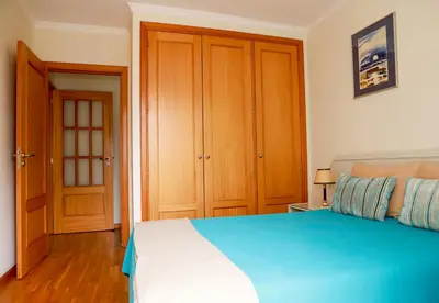 a bedroom with a blue and white bed and wooden cabinets at Apartamento Infante in Funchal