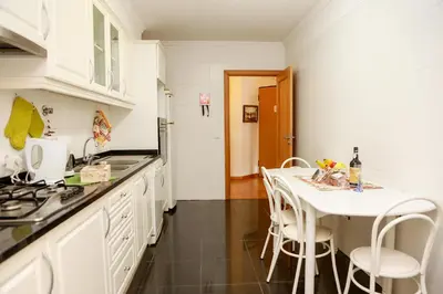 a kitchen with a table and white cabinets and a table and chairs at Apartamento Infante in Funchal