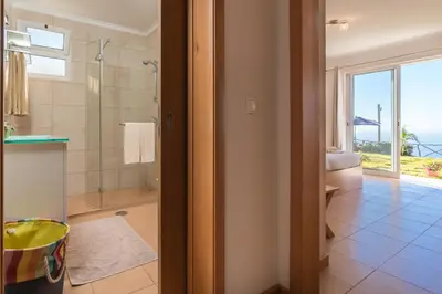 a bathroom with a shower and a glass door at Casa Sol e Vista in Arco da Calheta