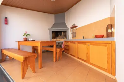 a kitchen with a table and benches and a fireplace at Casa Sol e Vista in Arco da Calheta